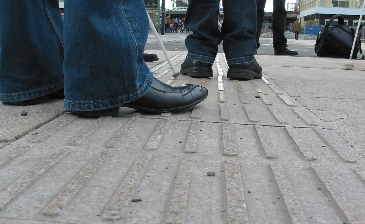 Mitglieder des GFUV testen auf einer Baustelle f&uuml;r eine Stra&szlig;enbahnhaltestelle einen neuen Leitstreifen